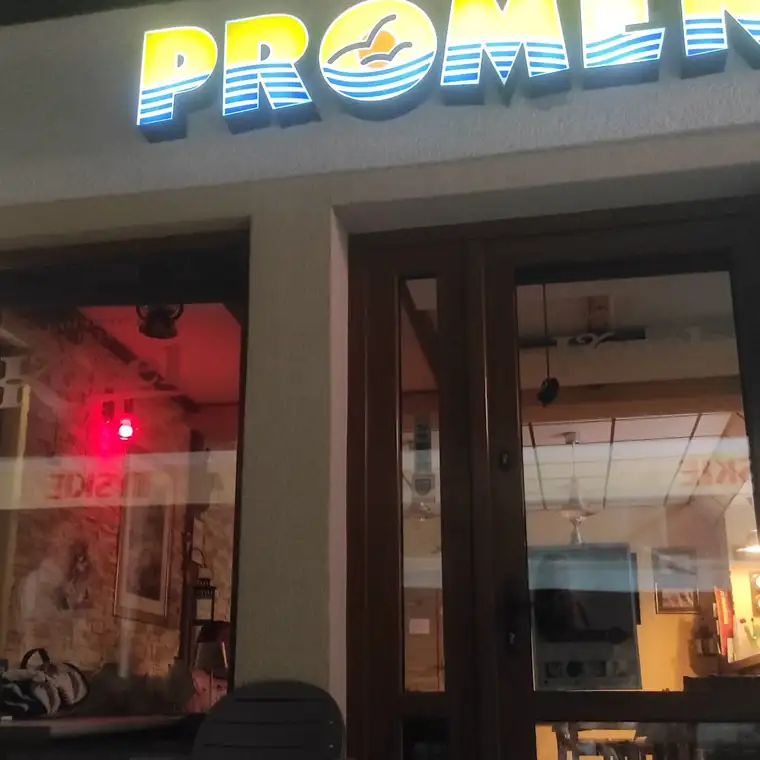 Wejście do baru Promenada wieczorem z podświetlonym szyldem